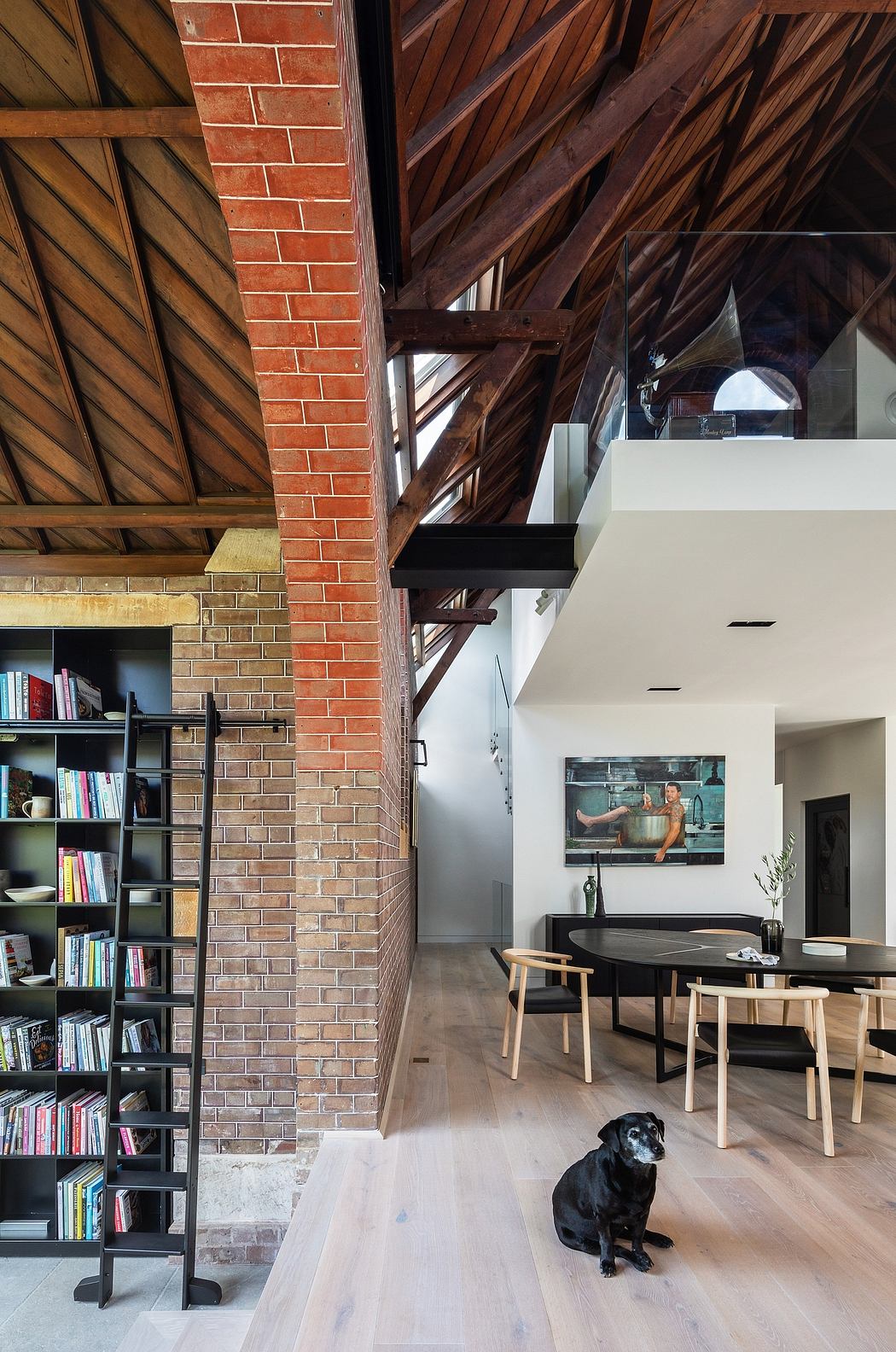 A cozy and modern loft space with brick walls, wooden beams, and a built-in bookshelf.