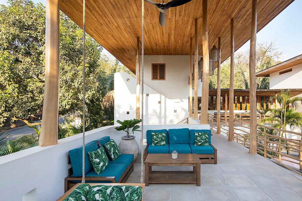 Modern outdoor patio with wooden ceiling, hanging sofa, and lush greenery.