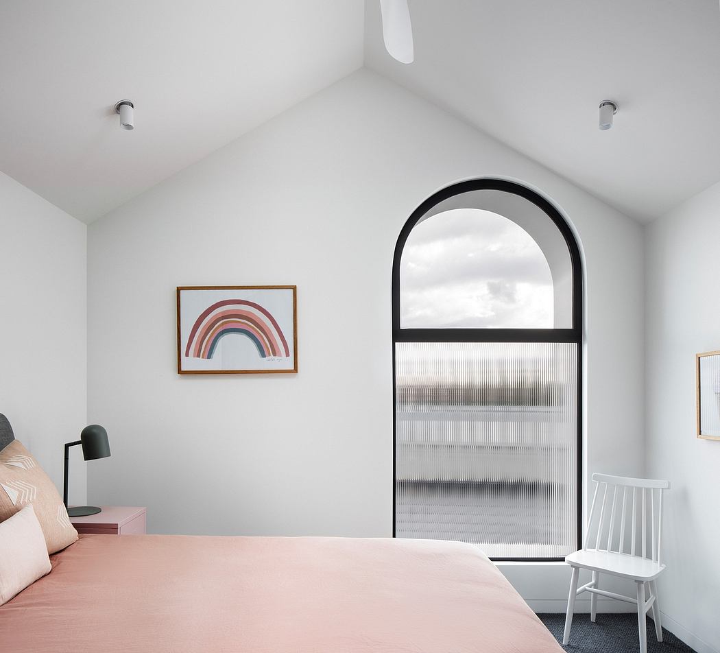 Minimalist bedroom with arched window, abstract artwork, and modern furnishings.