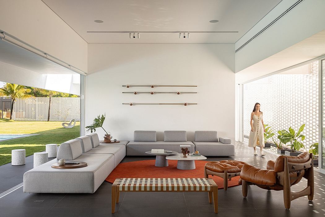 A modern, open-concept living room with sleek furniture, wood accents, and large windows overlooking lush greenery.