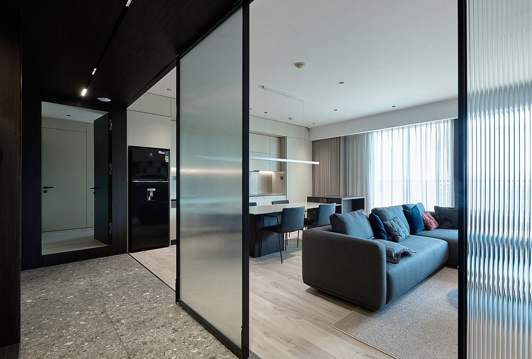 Modern apartment interior with sleek black sliding doors, blue sofa, and minimalist decor.