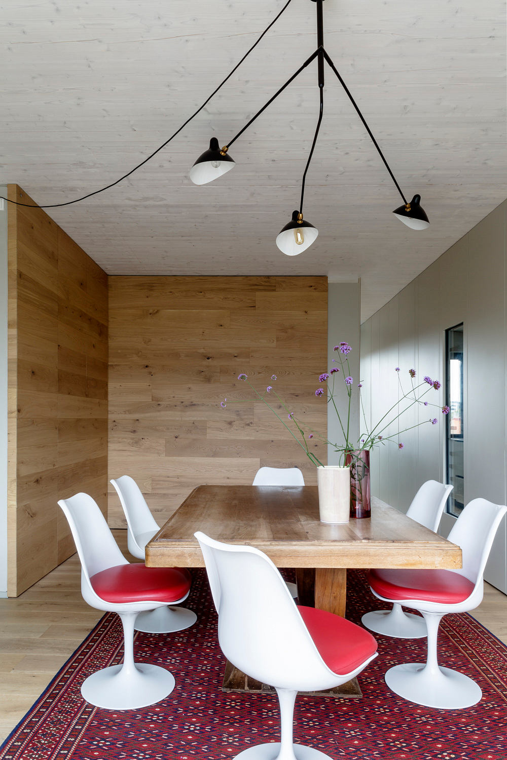 Contemporary dining space with wooden accents and white chairs.