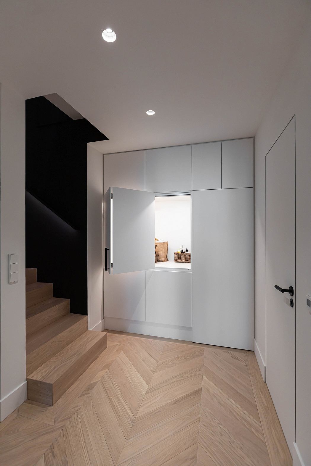Sleek hallway with herringbone floor and minimalist cabinets.