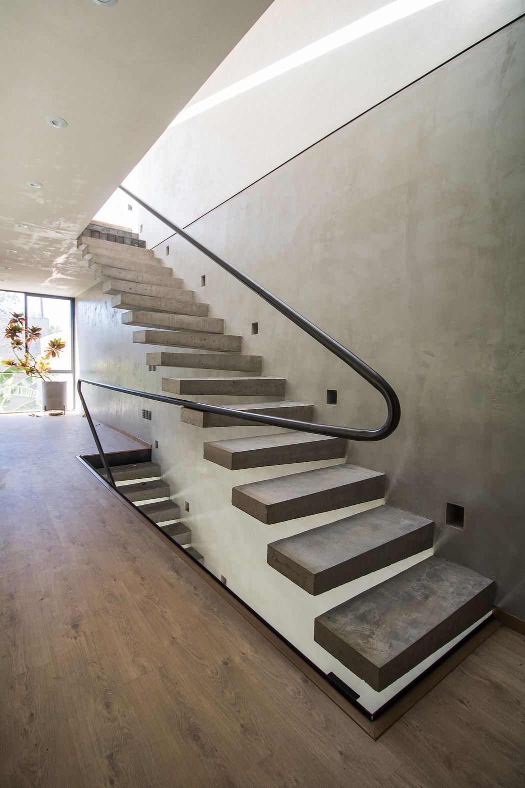Modern staircase with concrete steps and a metal handrail in a minimalist interior.