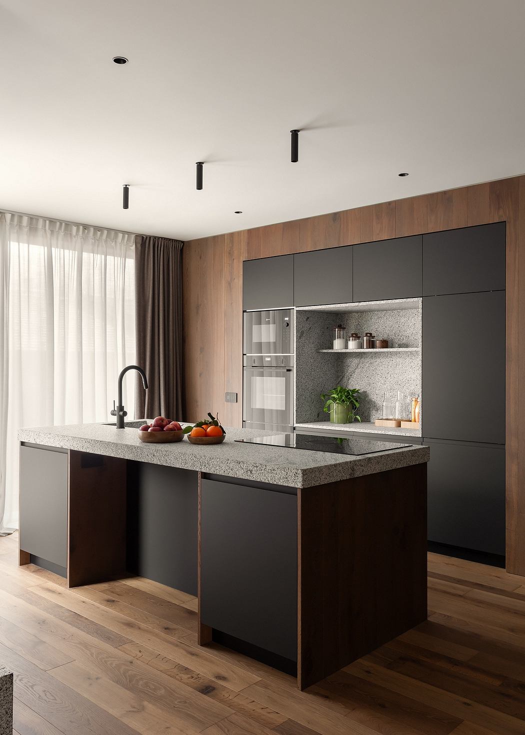 Modern kitchen with dark cabinets, island, and wooden floor.