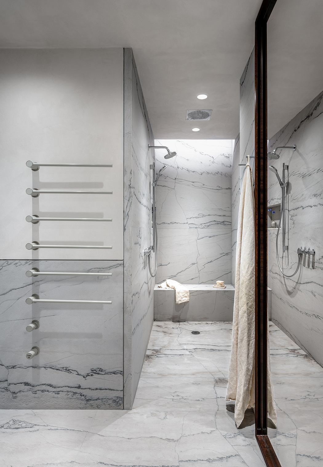 Sleek modern bathroom with marble walls, towel rack, and glass shower enclosure.