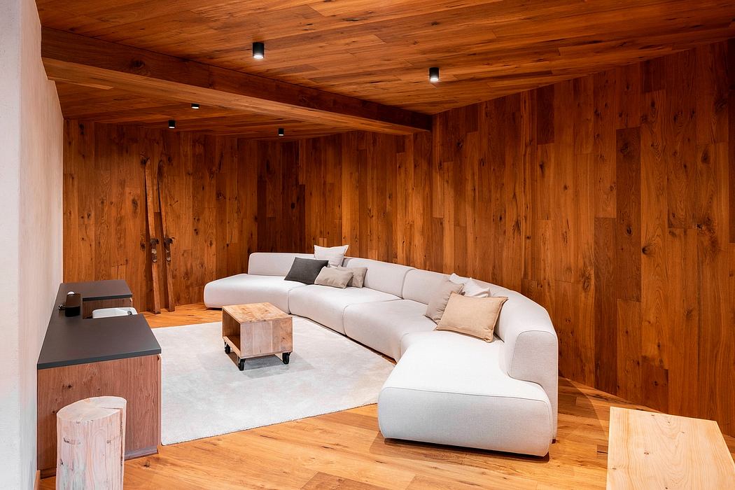 A cozy, rustic living room with warm wood paneling, a sectional sofa, and accent tables.