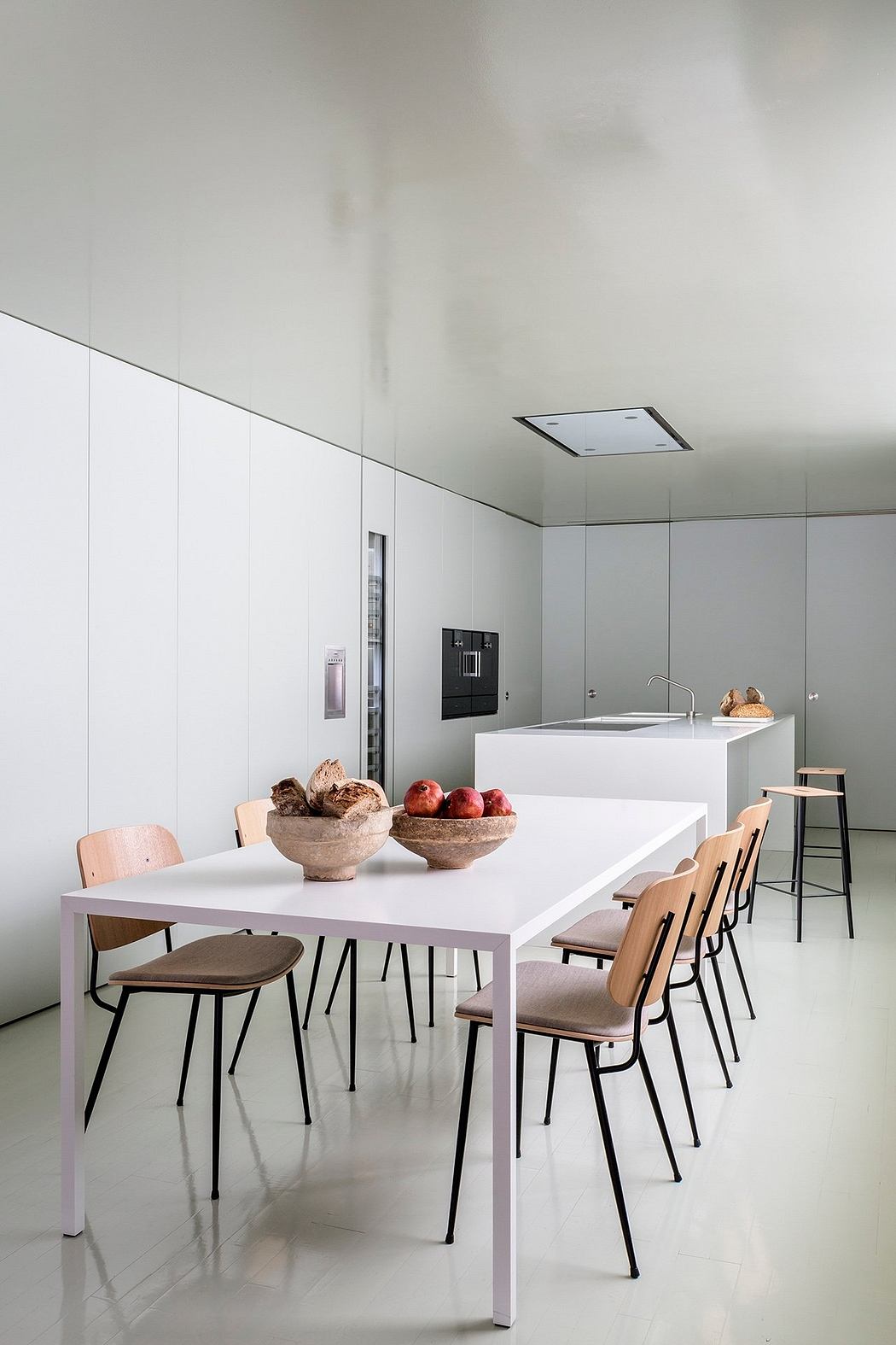 A modern, minimalist kitchen and dining area with geometric furniture and decor.