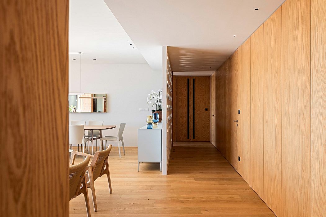 Modern hallway with wooden walls and flooring, leading to a dining area.