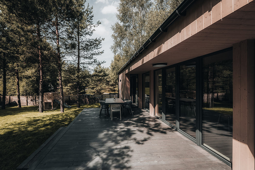 Rustic wooden cabin with large windows overlooking a lush forest patio.
