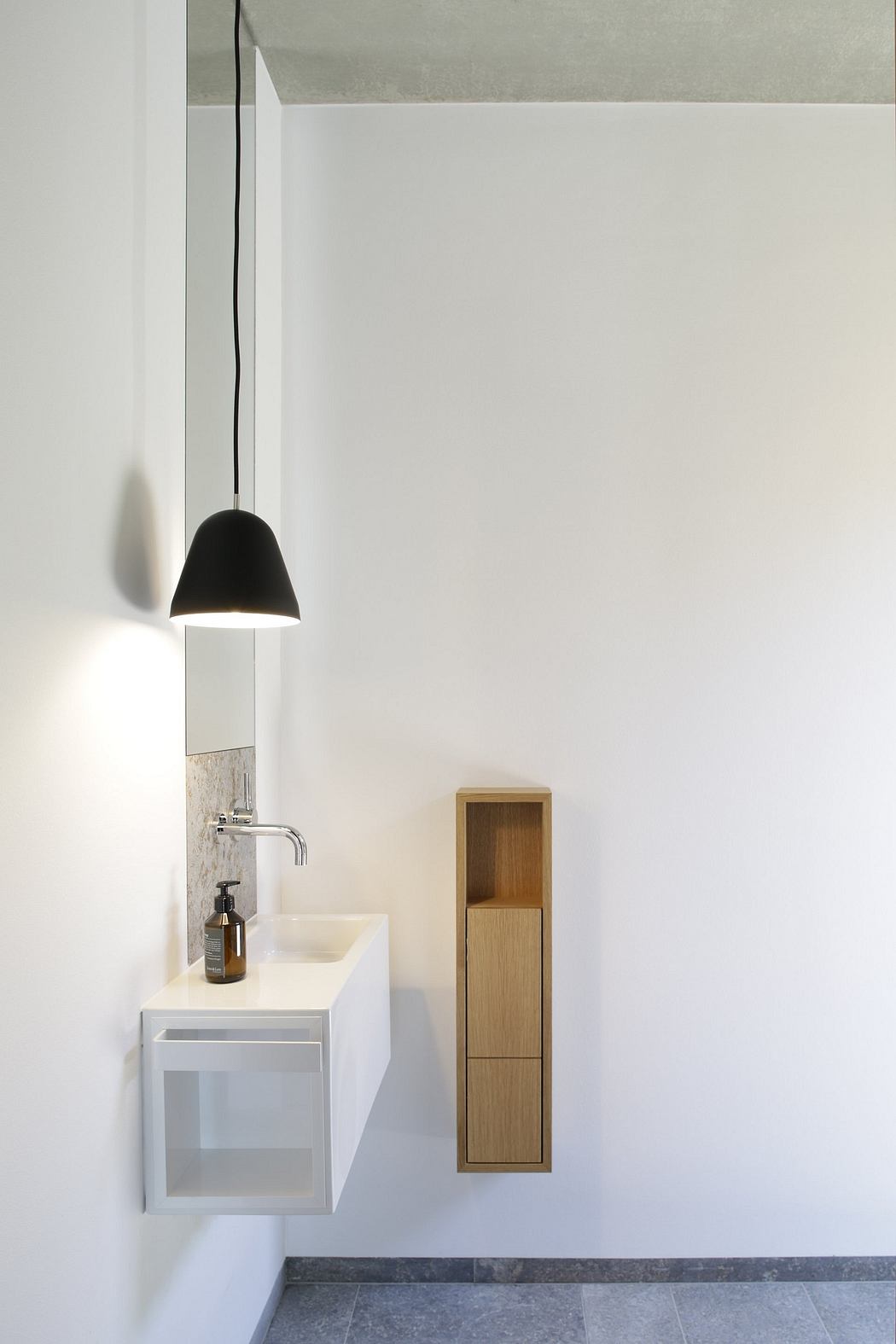 Minimalist bathroom corner with sleek fixtures and wood accents.
