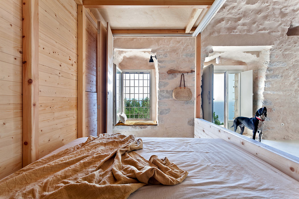 A cozy bedroom with wooden walls, stone accents, and large windows overlooking nature.