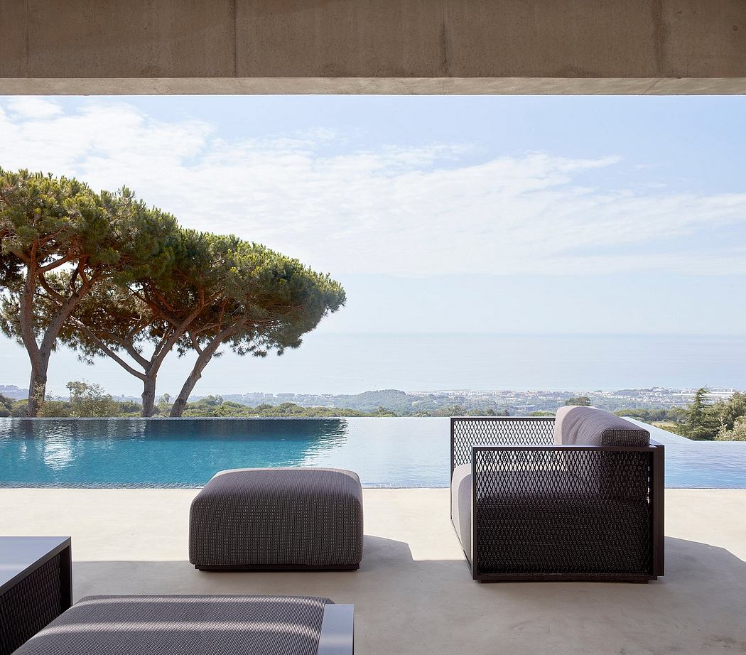 Modern terrace with furniture overlooking an infinity pool and scenic view.