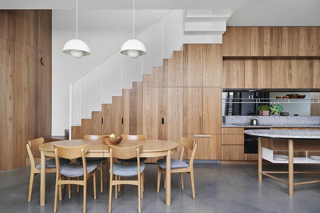 Modern dining area with wooden walls, staircase, and minimalist furniture.