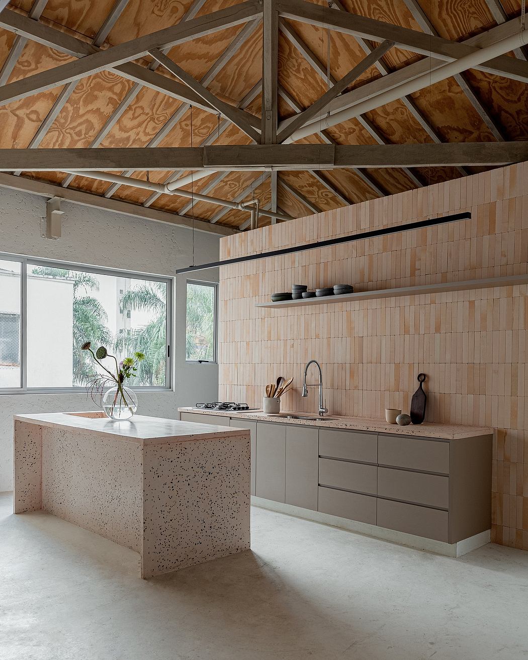 Minimalist kitchen with exposed wooden beams and terrazzo island.