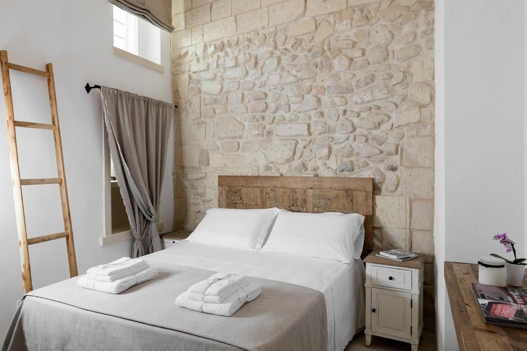 Rustic stone wall, plush bedding, and warm wooden accents create a cozy retreat.
