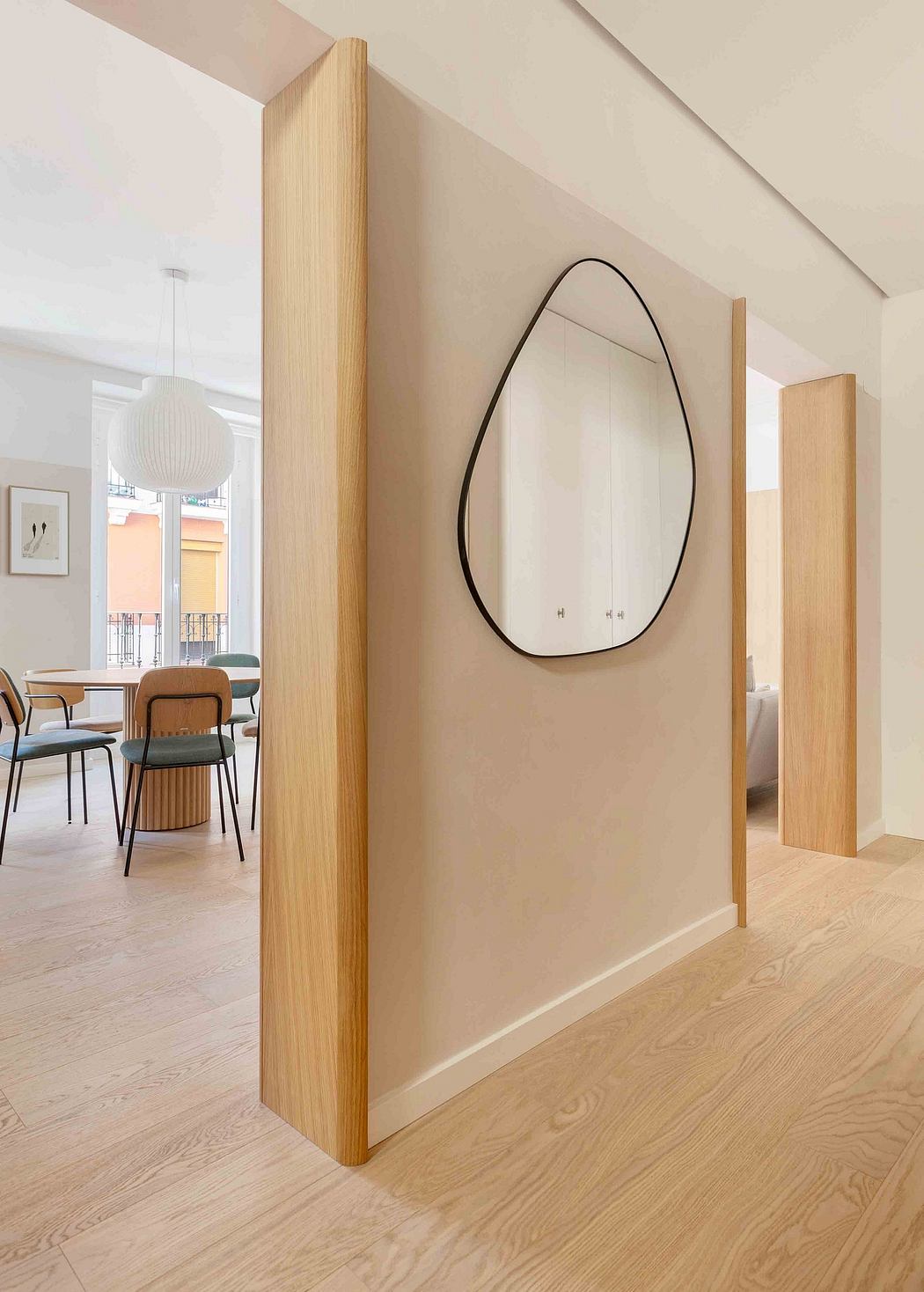 Striking architectural features, including a curvilinear mirror and wood columns, complement the minimalist decor.