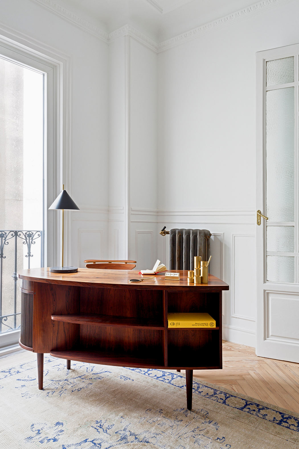 Elegant room with a vintage wooden desk, white walls, and a balcony door