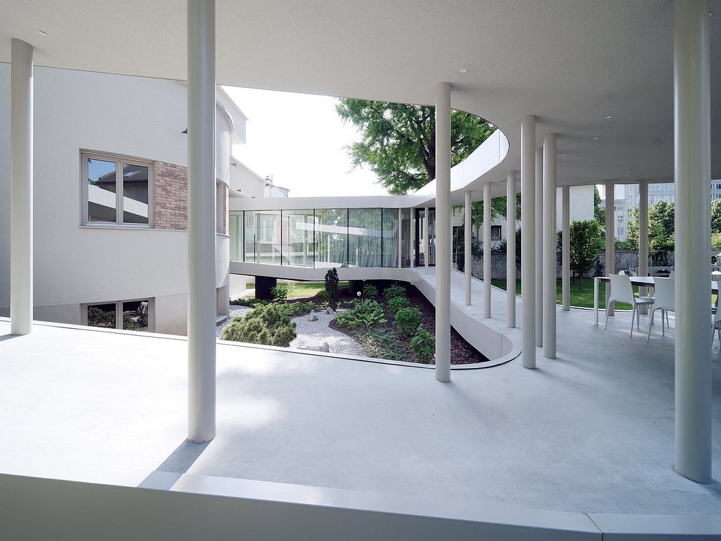 A modern interior with glass walls, columns, and a green courtyard garden.