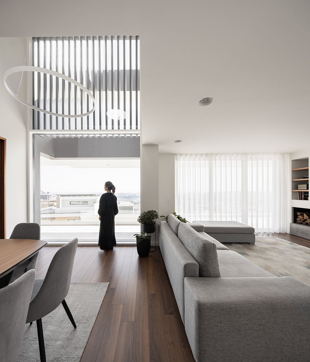 Minimalist living space with floor-to-ceiling windows, wood flooring, and modern furniture.