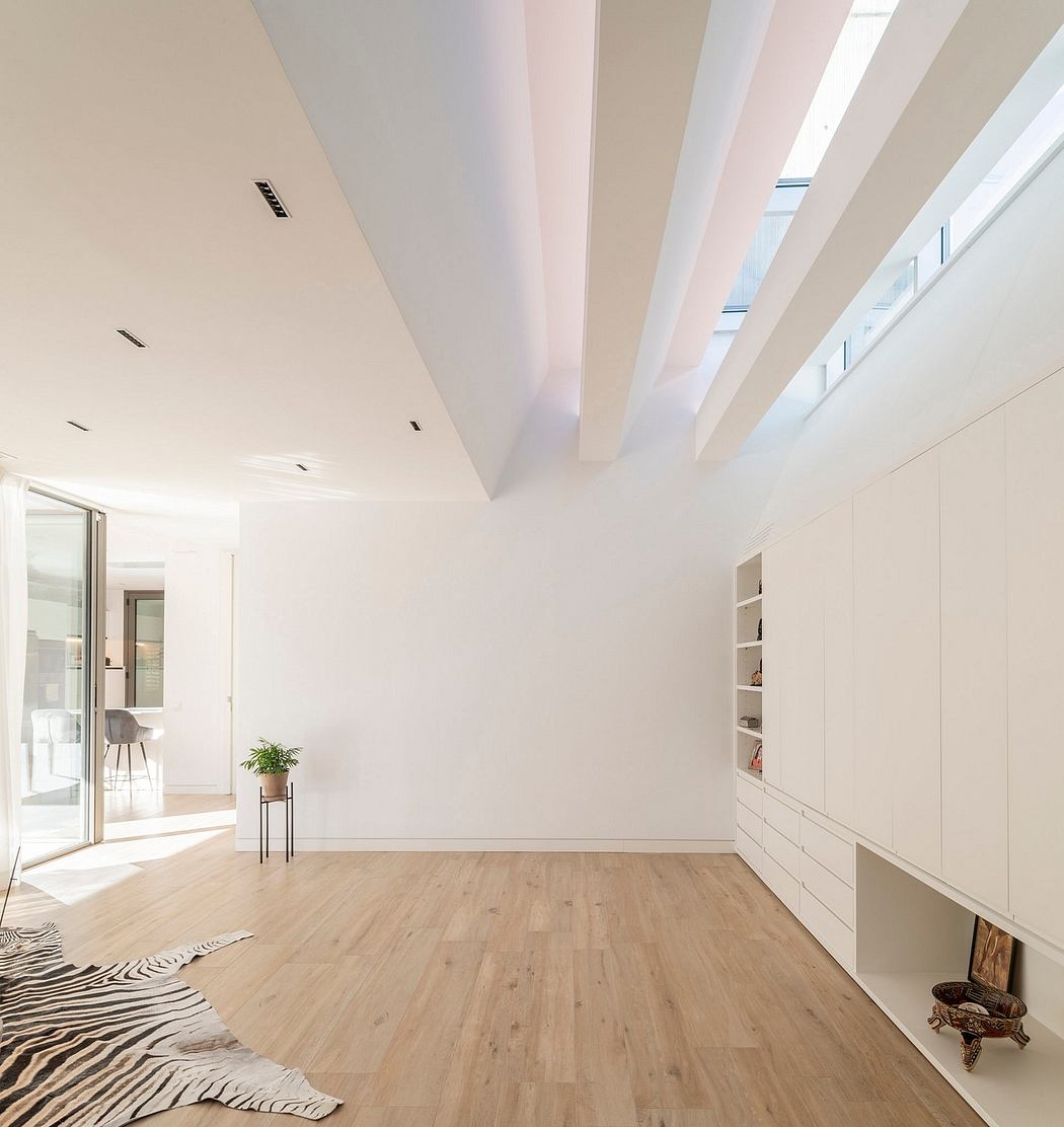 Minimalist interior with skylights, white walls, and wooden floor.