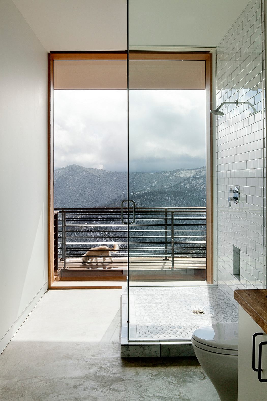 Bathroom with floor-to-ceiling glass door leading to balcony with mountain view.