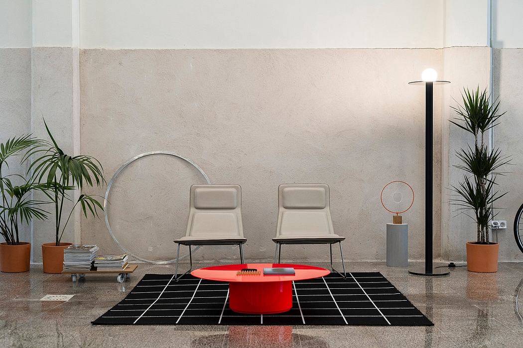 Modern lobby with a red table, two chairs, plants, and floor lamp.