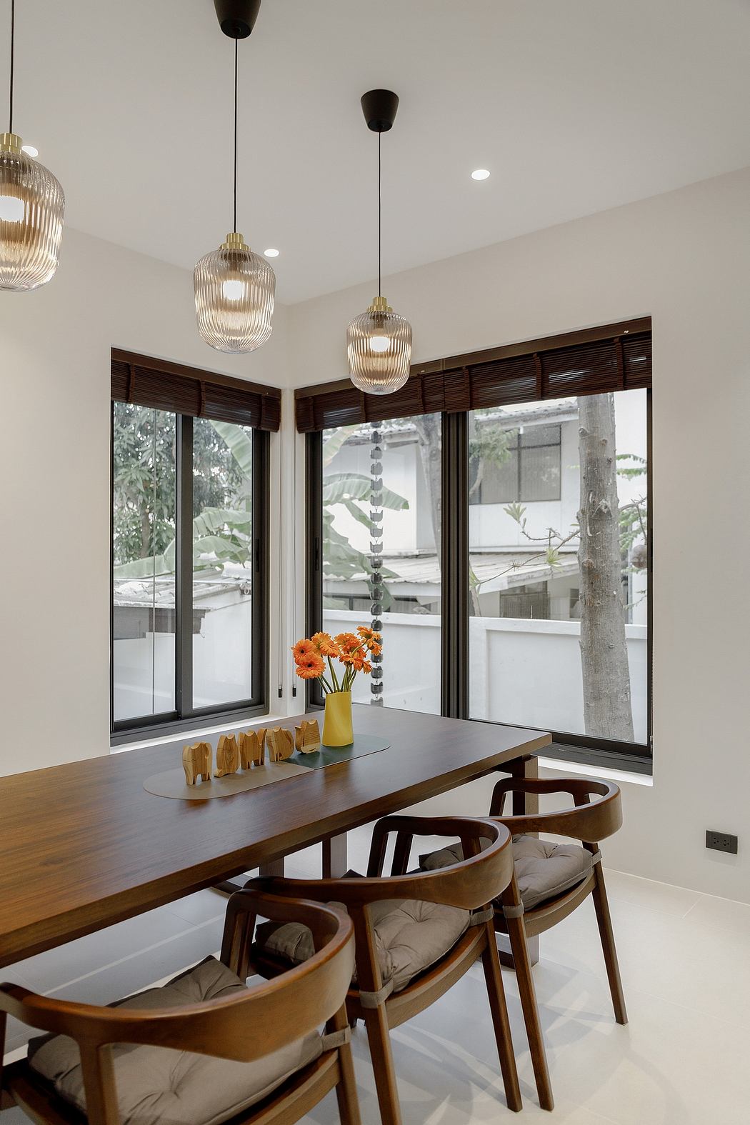 Contemporary dining space with wooden table, designer chairs, and pendant lights.
