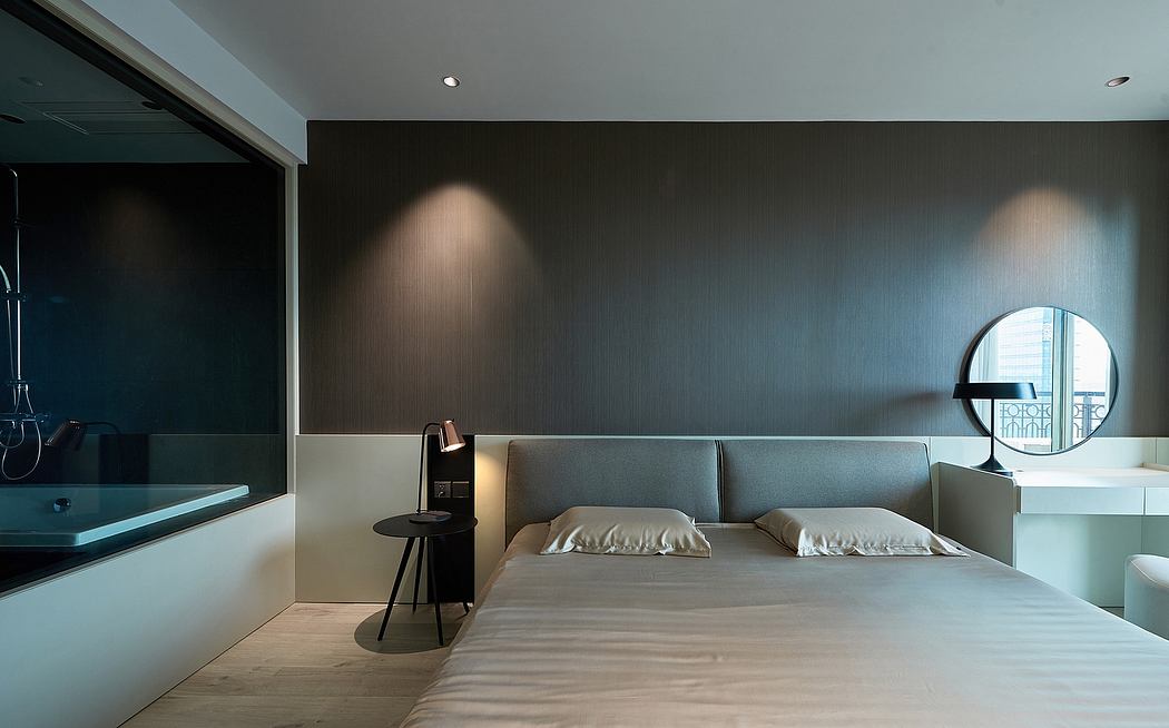 A modern bedroom with minimalist furnishings, circular mirror, and recessed lighting.