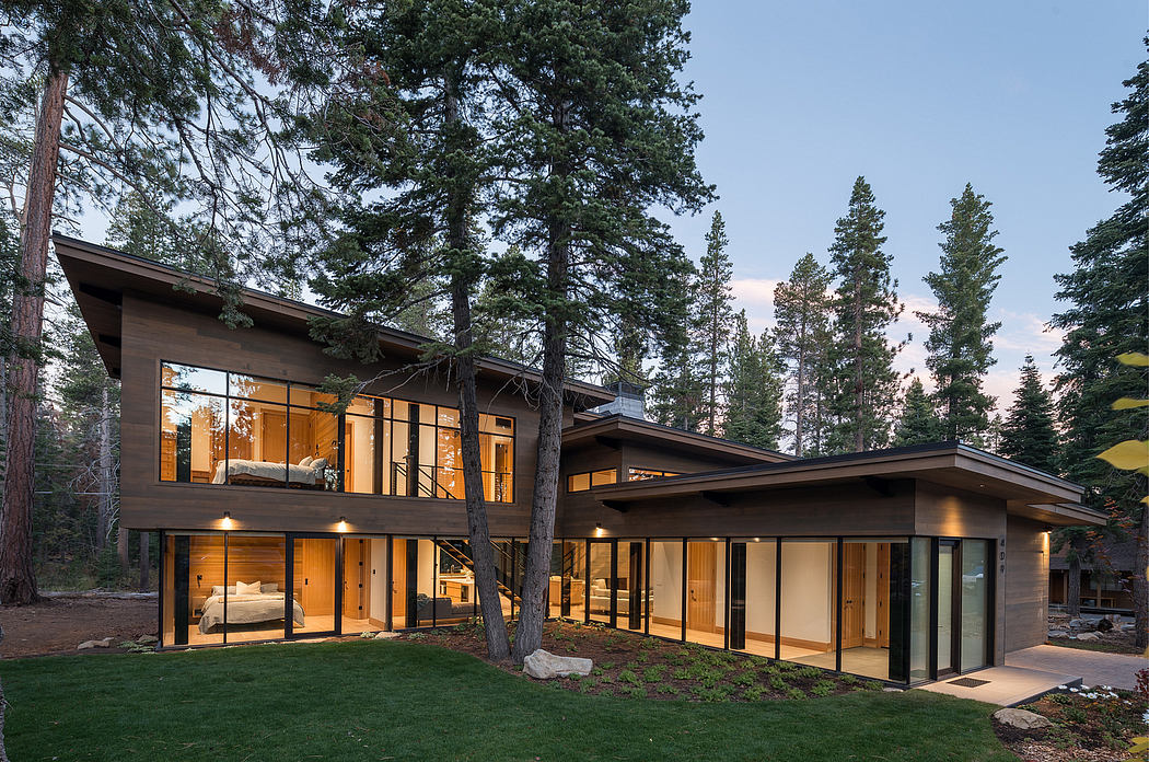 Modern house with large windows surrounded by trees at dusk.