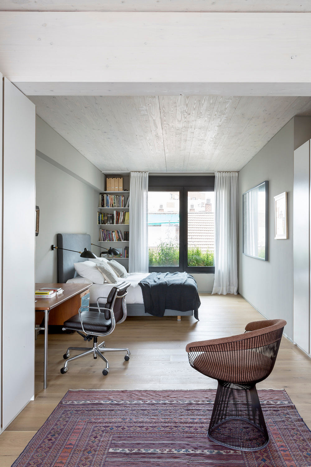 Minimalist bedroom with exposed concrete ceiling and wooden accents.