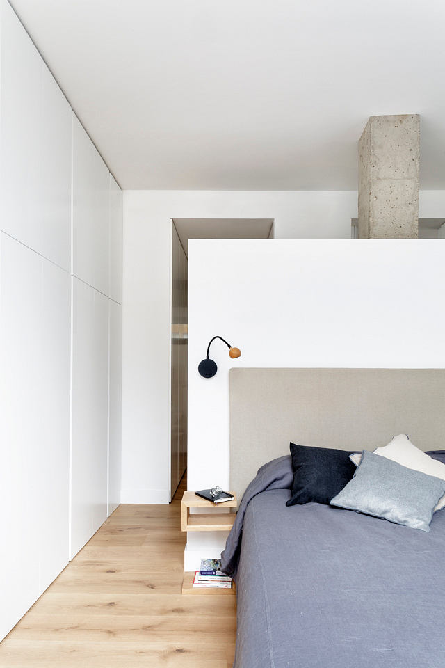 Minimalist bedroom with sleek white walls and wooden floor.