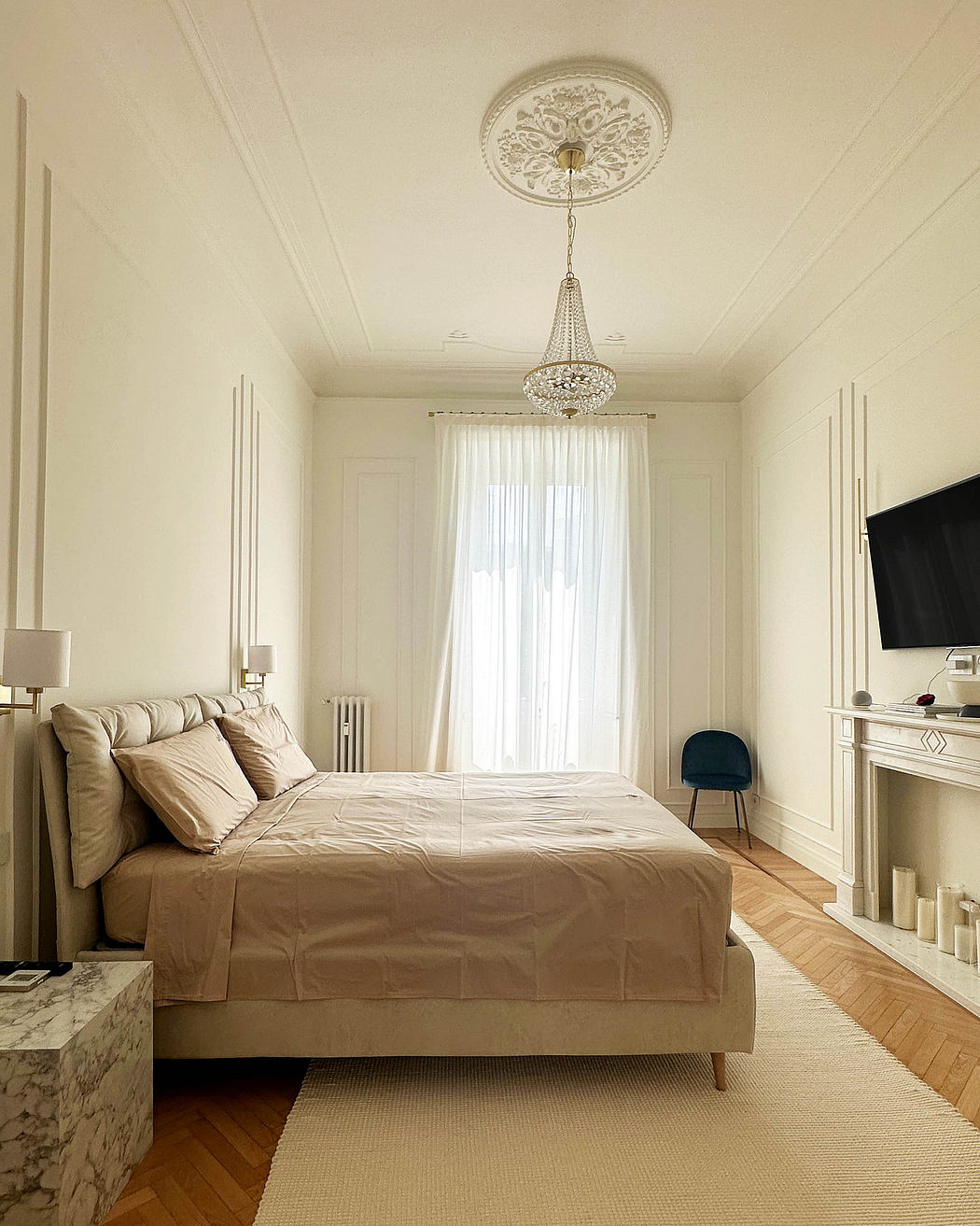 Elegant bedroom with a chandelier, neutral tones, and classic decor.