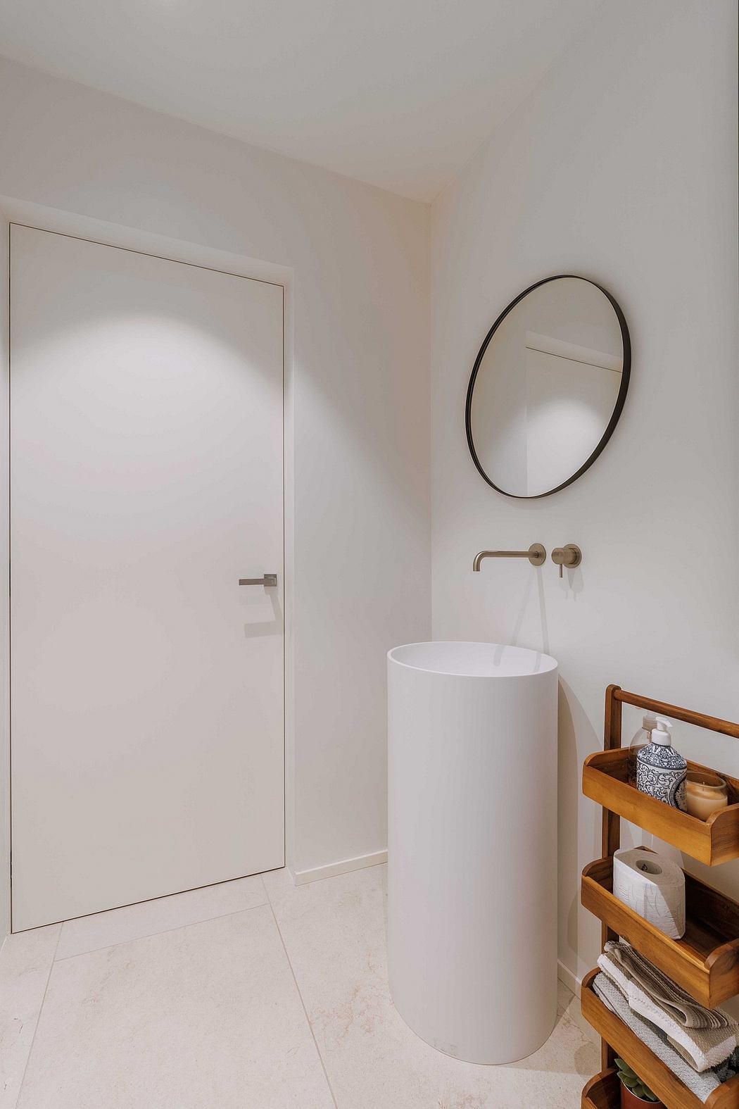 Minimalistic bathroom with a cylindrical sink and circular mirror.