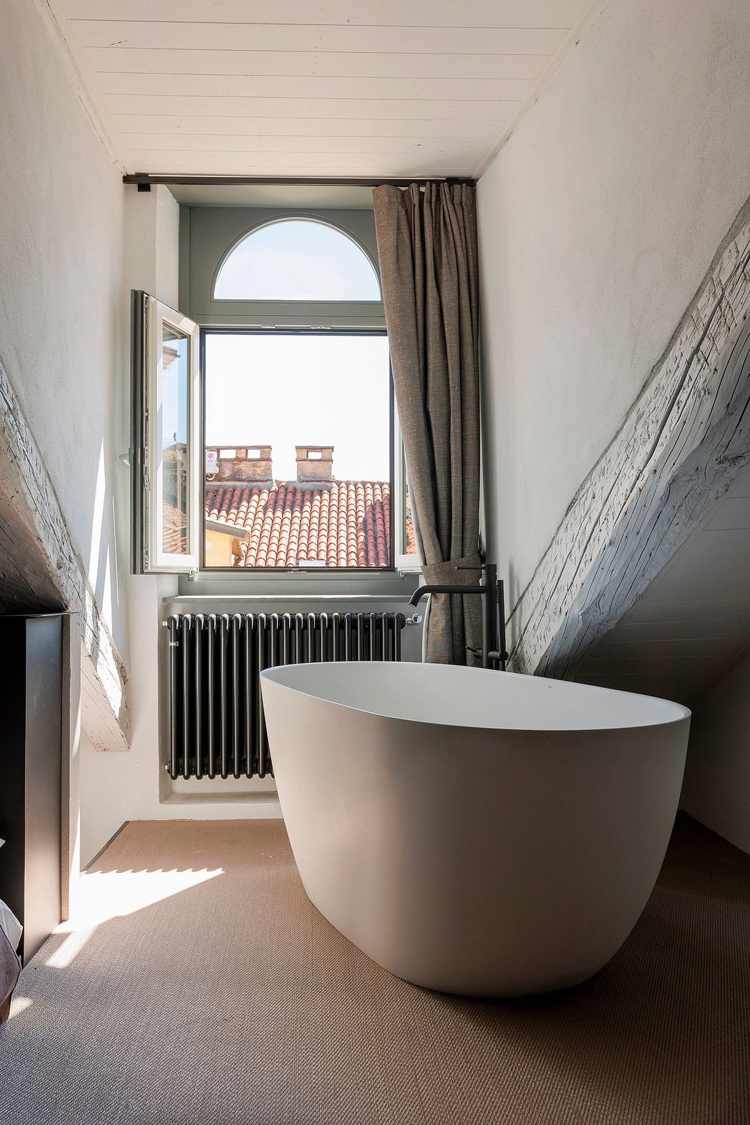 Spacious bathroom with a freestanding tub, arched window, and textured walls.