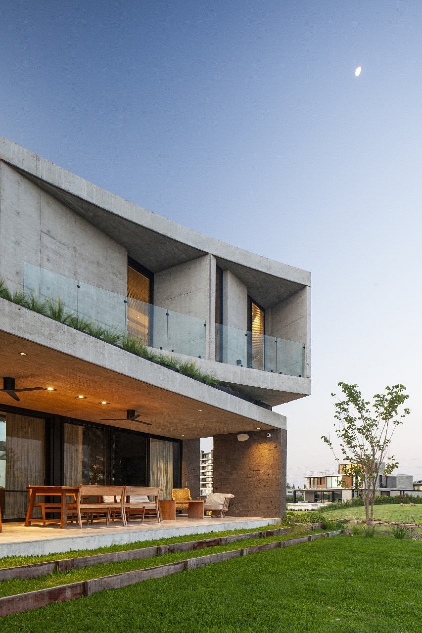 Contemporary concrete house with cantilevered upper floor and grass rooftop.