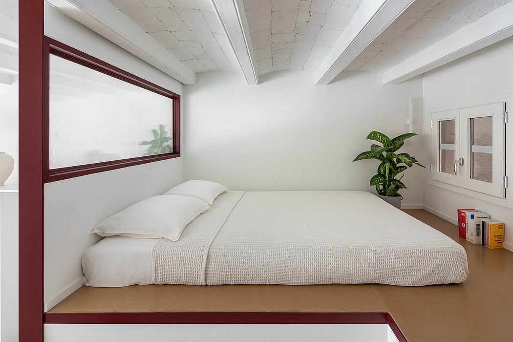 Minimalist attic bedroom with white walls, exposed beams, and a large window.