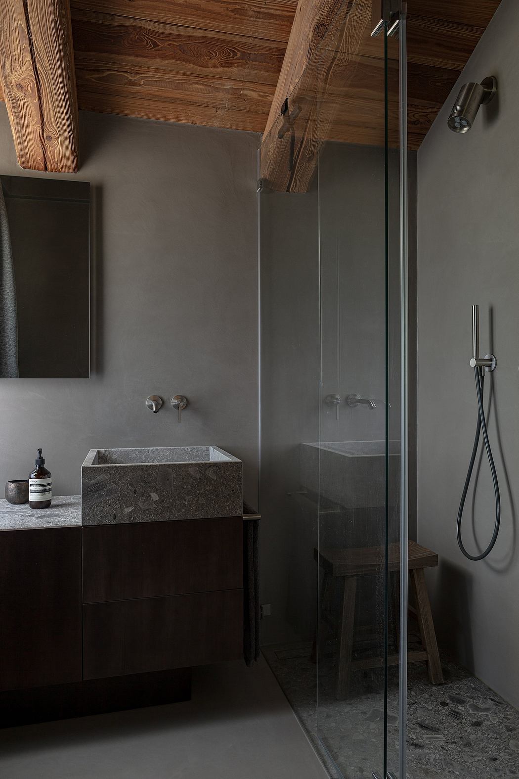 Modern bathroom with a wooden ceiling, glass shower, and stone sink.