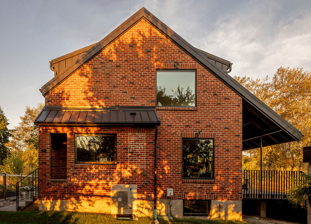 Gabled brick house with large windows at sunset.