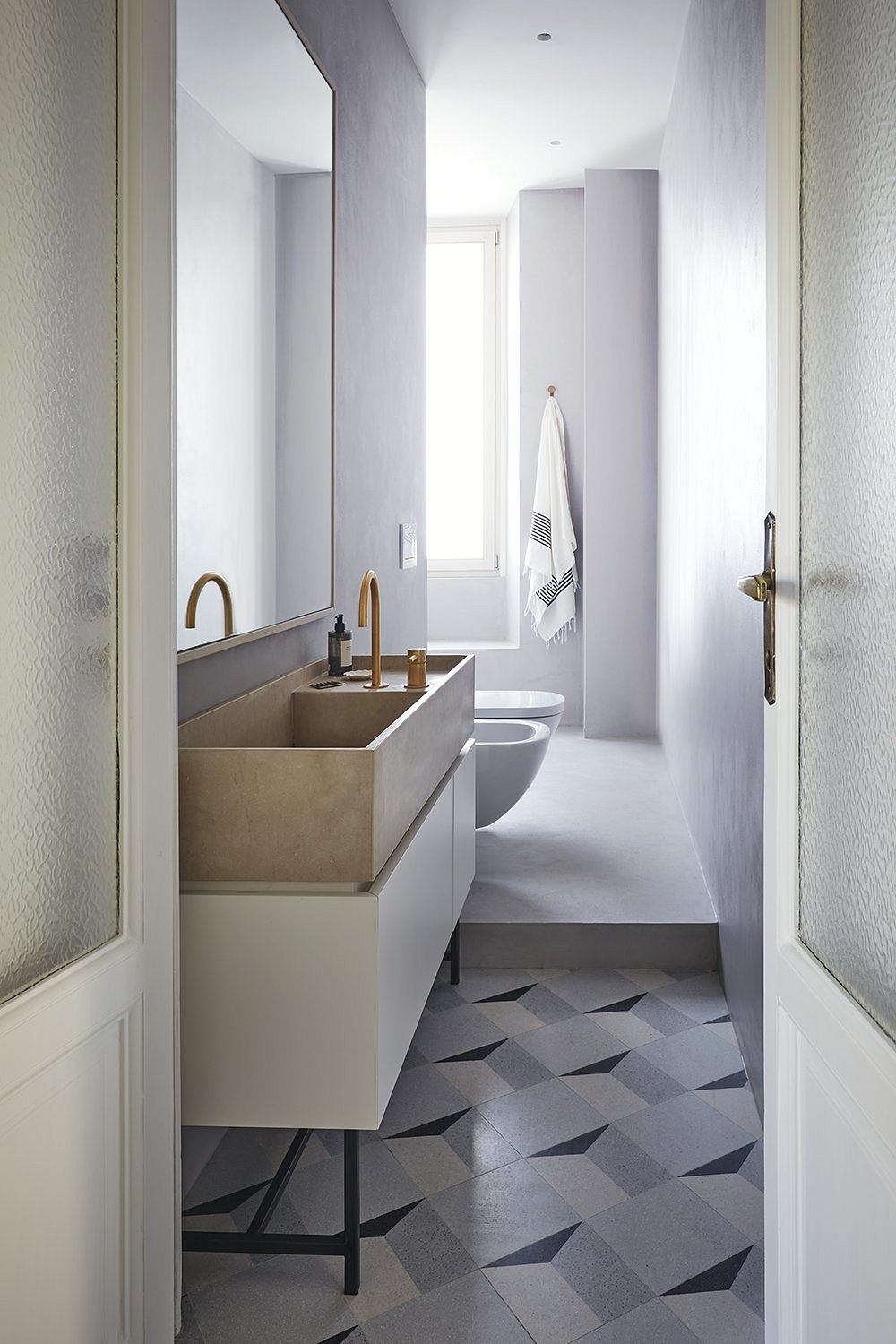 Minimalist bathroom with monochrome tiled floor, built-in vanity, and sleek fixtures.