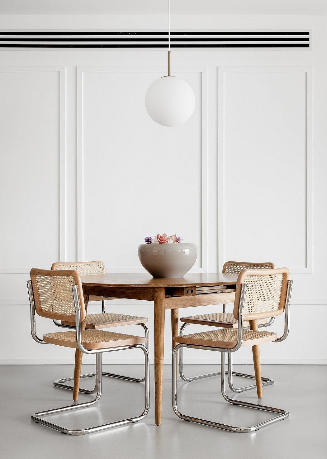 Modern dining area with a round table, four chairs, and a pendant light.