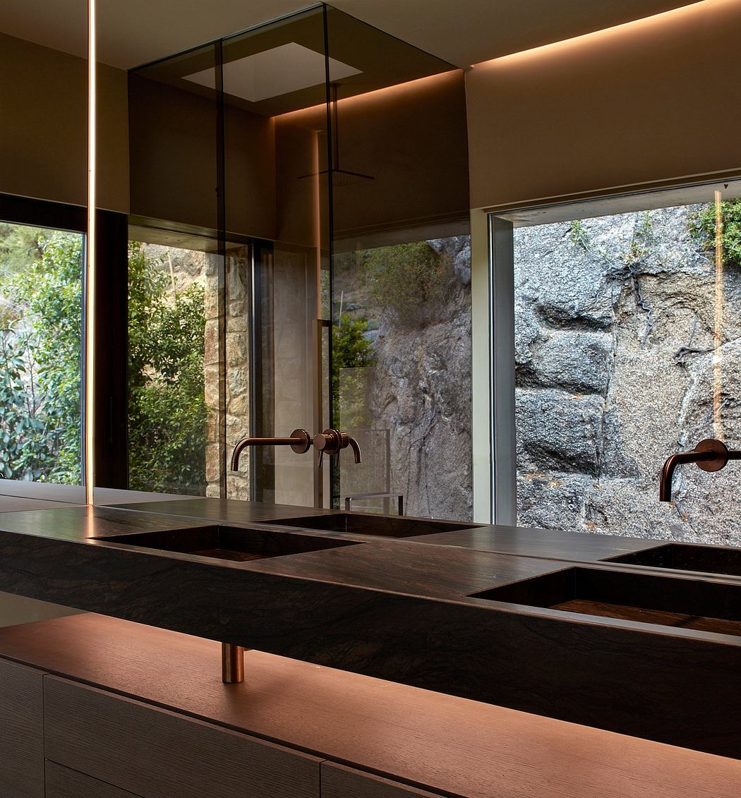 Modern kitchen with black countertops, copper fixtures, and a garden view.