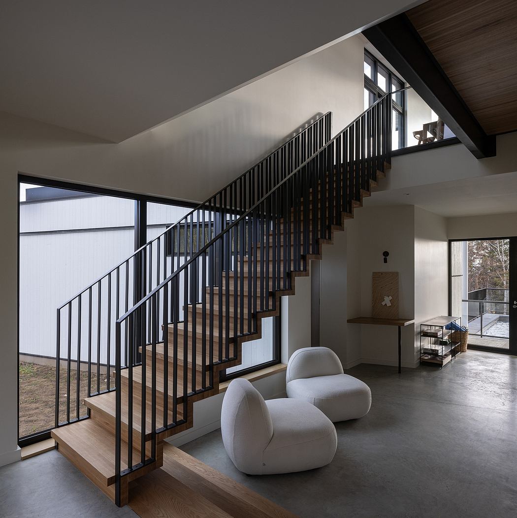 Modern interior with a wooden staircase and minimalist white chairs.