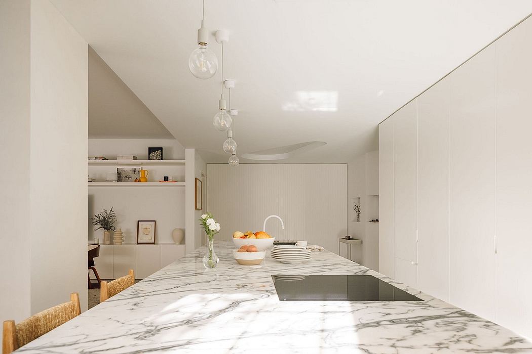 Elegant, minimalist kitchen with sleek marble countertop, pendant lights, and open shelving.