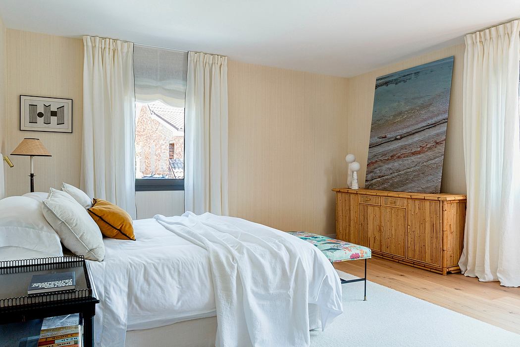 Cozy bedroom with neutral tones, artwork, and natural wood furniture creating a tranquil space.