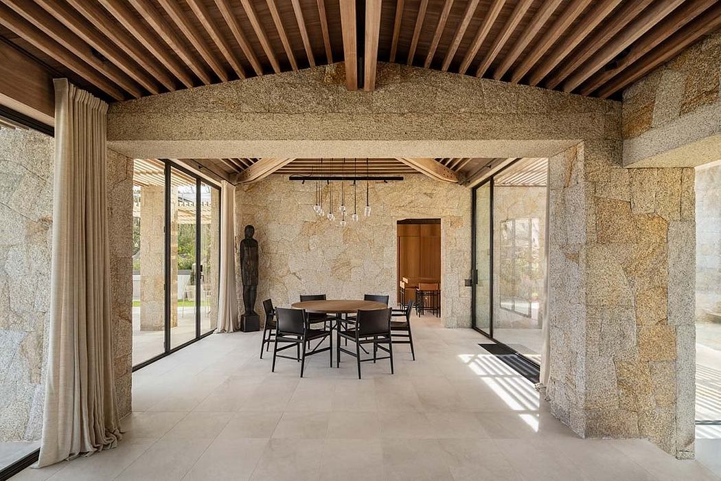 Elegant dining area with stone walls, wooden ceiling, and large windows.