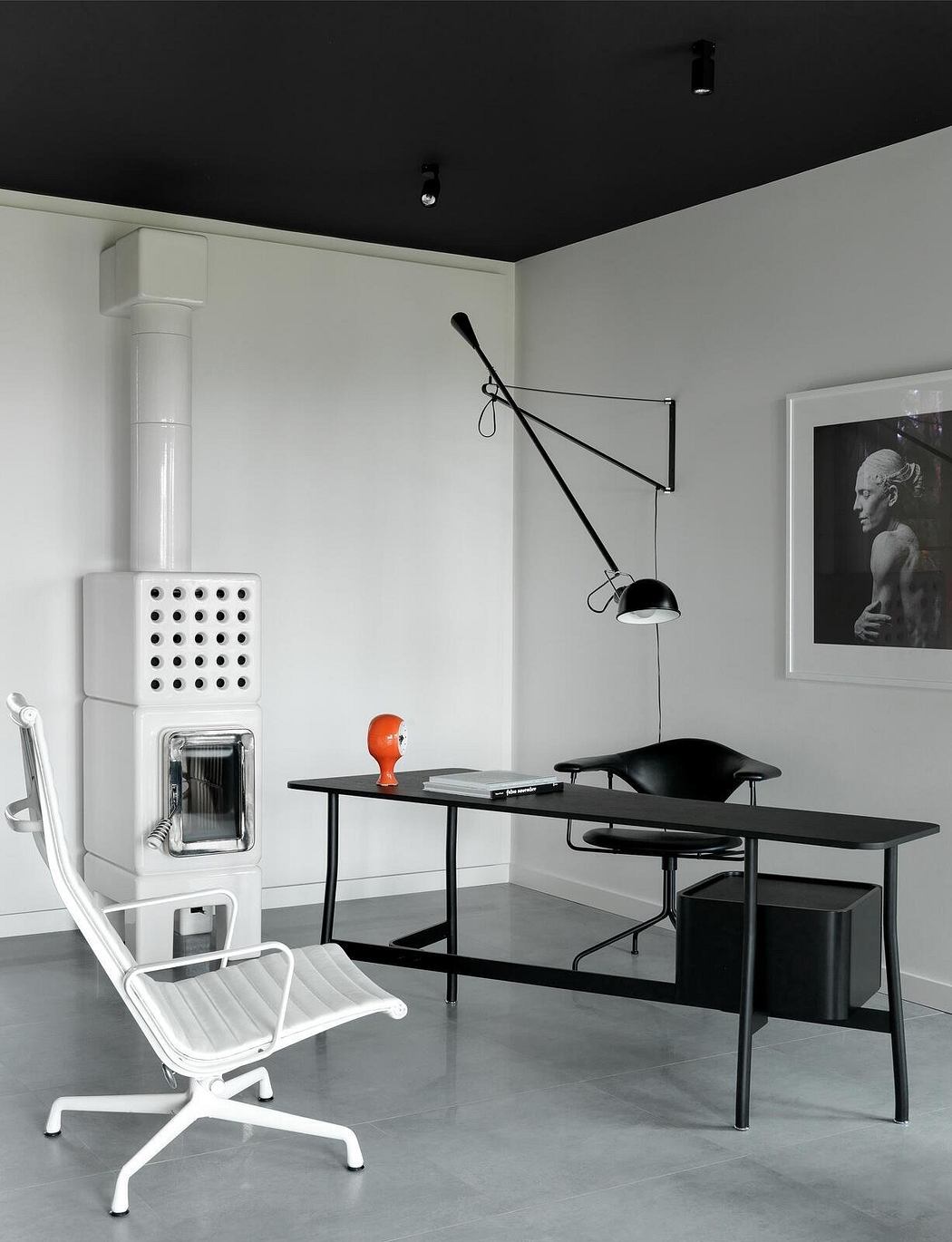 Minimalist office space with white walls, black furniture, and industrial lighting.