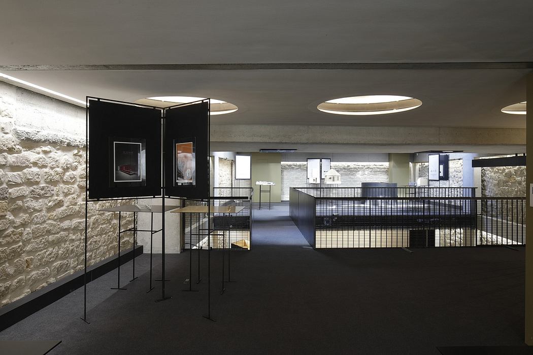 Modern gallery space with concrete walls, minimalist lighting, and metal railings.