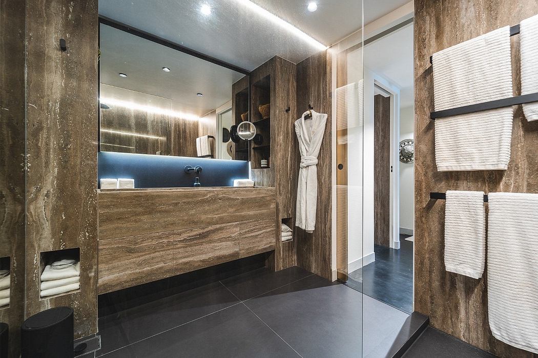 Contemporary bathroom with wooden vanity and backlit mirror.