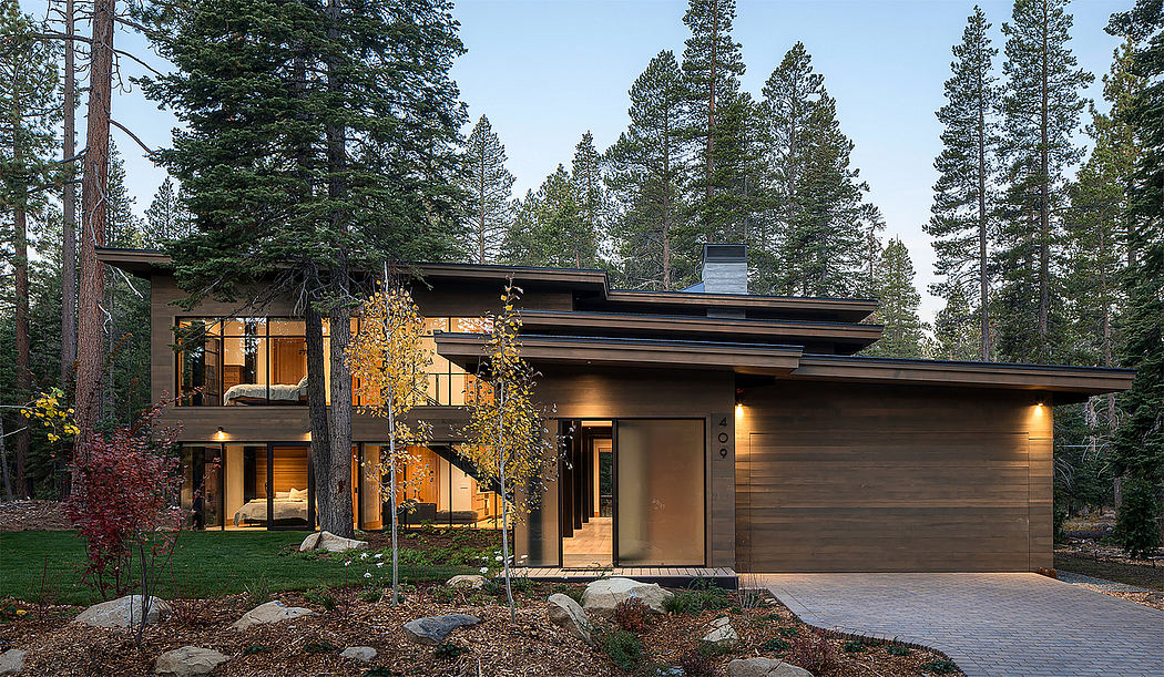 Contemporary house with large windows nestled among tall trees.